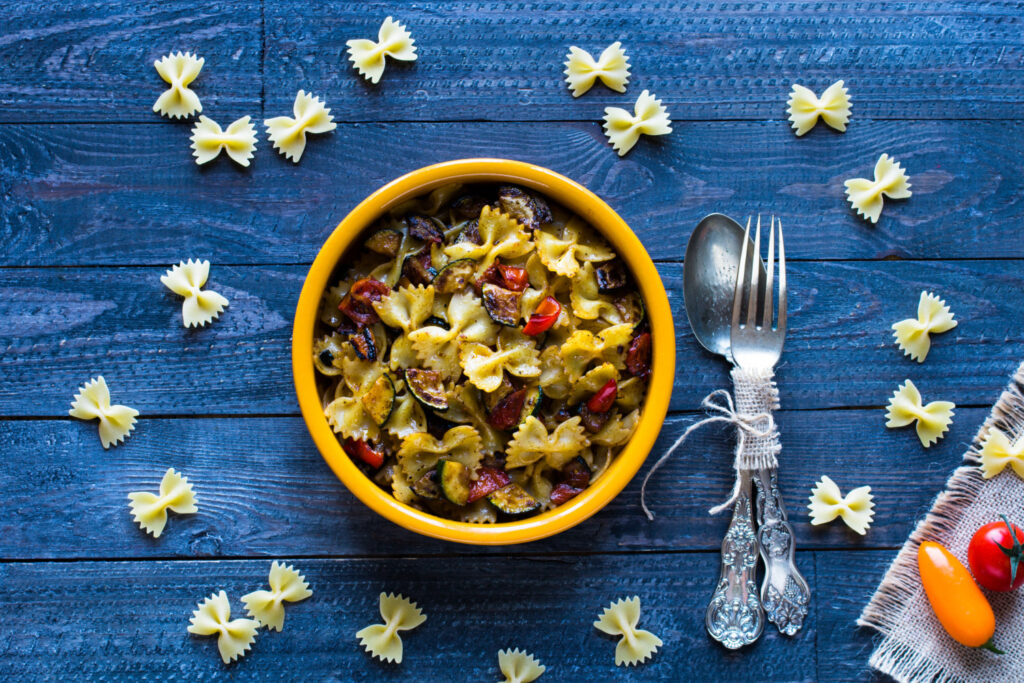 A vibrant bow tie pasta salad with cherry tomatoes, cucumbers, bell peppers, and feta cheese, tossed in a zesty dressing and garnished with fresh parsley.