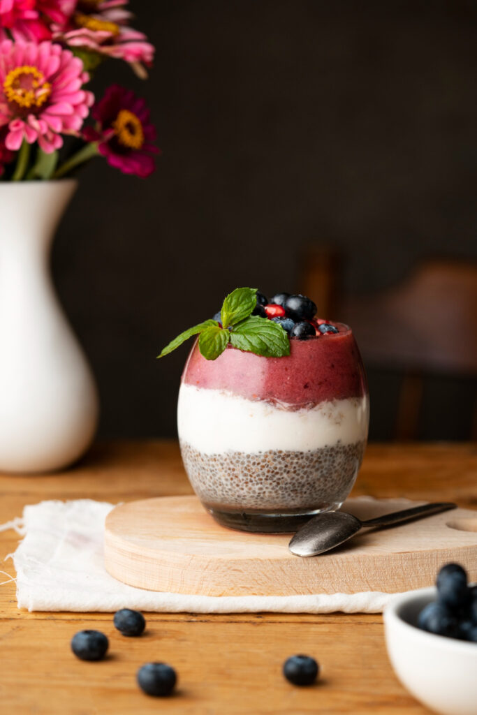 Matcha chia seed pudding with blueberries, kiwi, and coconut flakes in a glass jar.