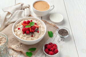 Healthy oatmeal topped with fresh berries, banana slices, granola, and honey on a rustic wooden table.