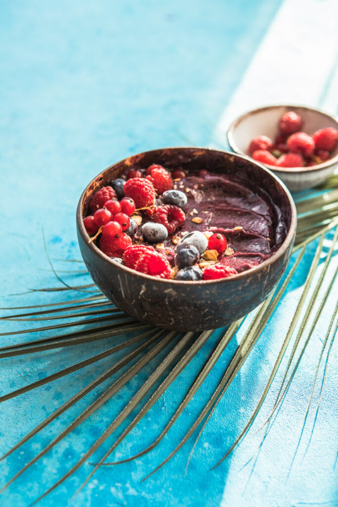 Açaí bowl smoothie with bananas, blueberries, granola, and chia seeds on a wooden table.