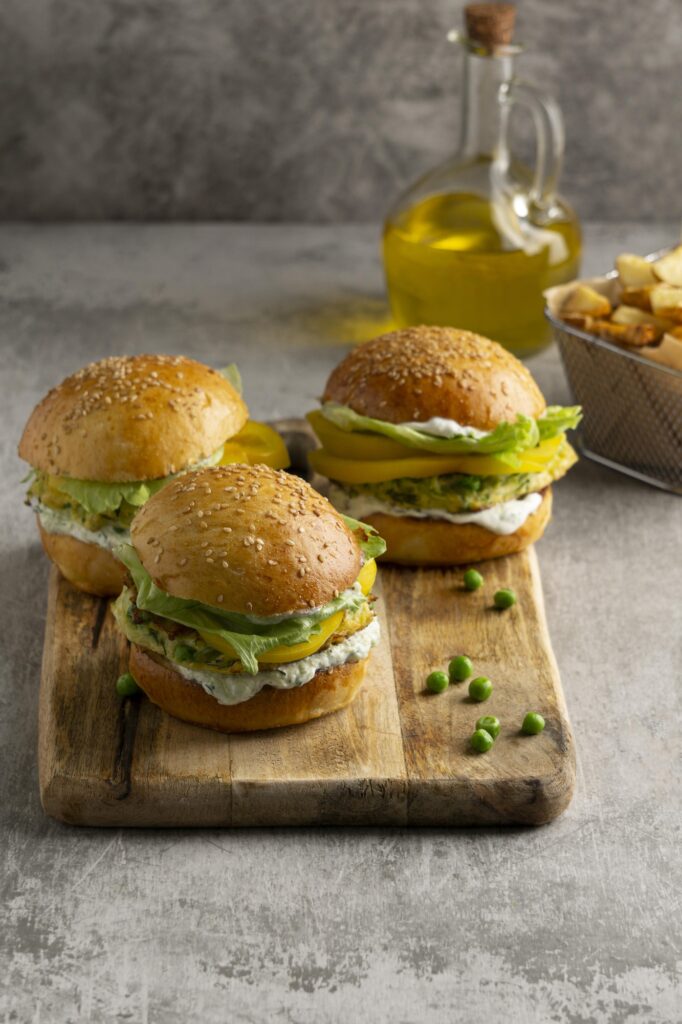 Golden sourdough hamburger buns on a wooden board with sesame seed topping.