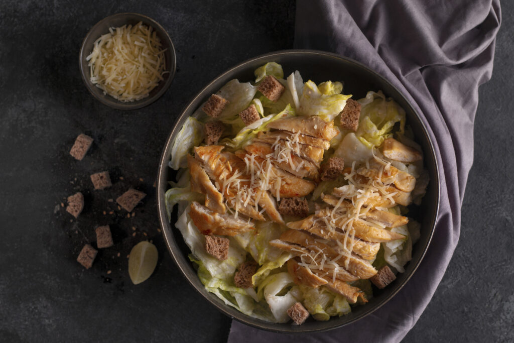 Bowl of Caesar pasta salad topped with croutons, Parmesan cheese, and creamy dressing