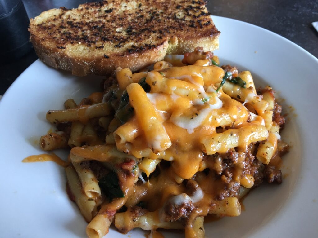 Philly cheesesteak pasta with steak, bell peppers, onions, and melted cheese served in a bowl.