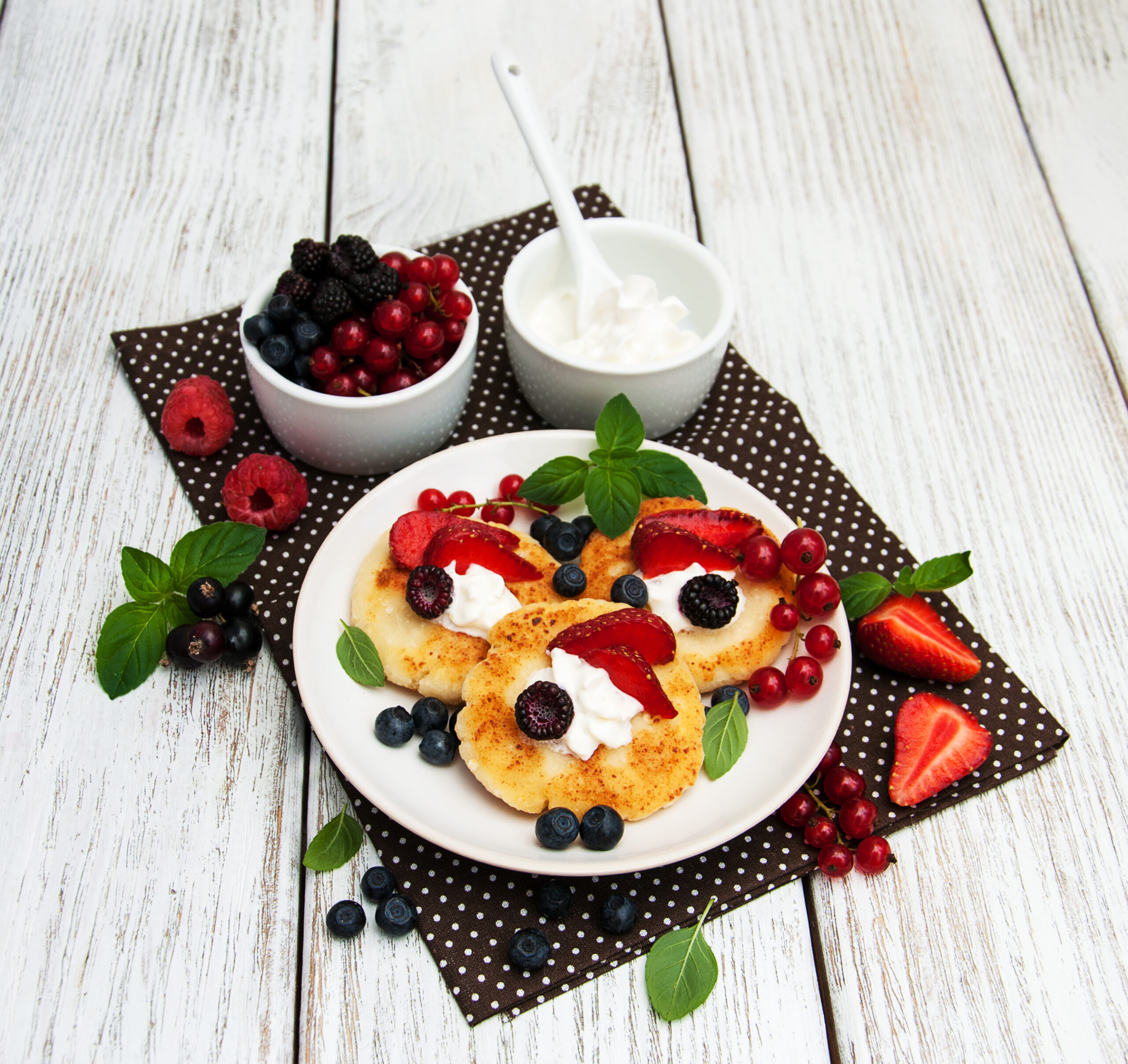 Fruit salad with strawberries, blueberries, pineapple, and bananas topped with Cool Whip in a glass bowl.