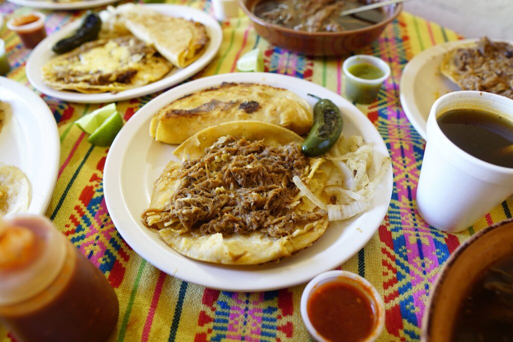 Mexican breakfast dish chilaquiles with eggs, avocado, cheese, and cilantro on a colorful plate.