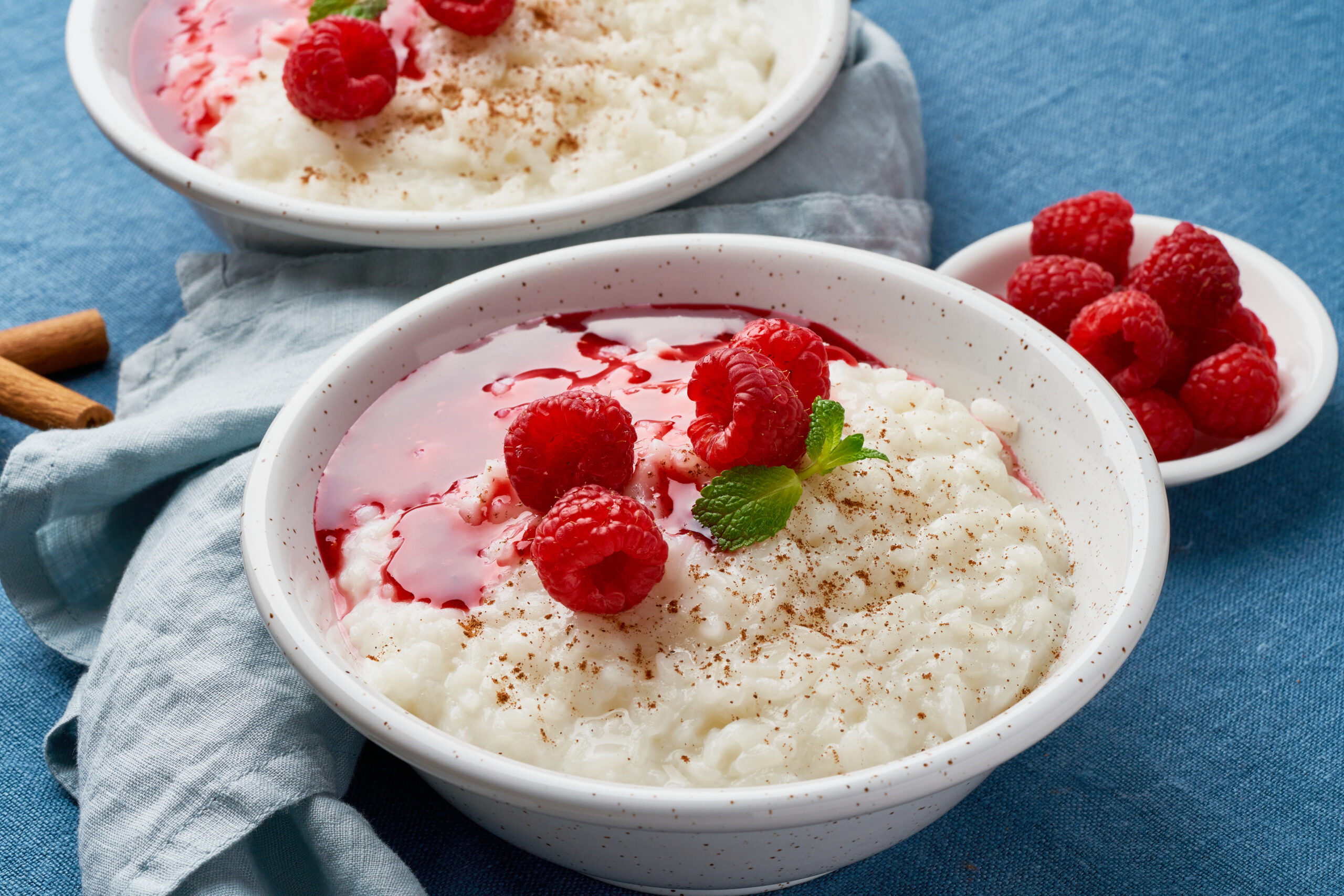 Creamy vegan rice pudding topped with fresh berries and cinnamon in a white bowl.