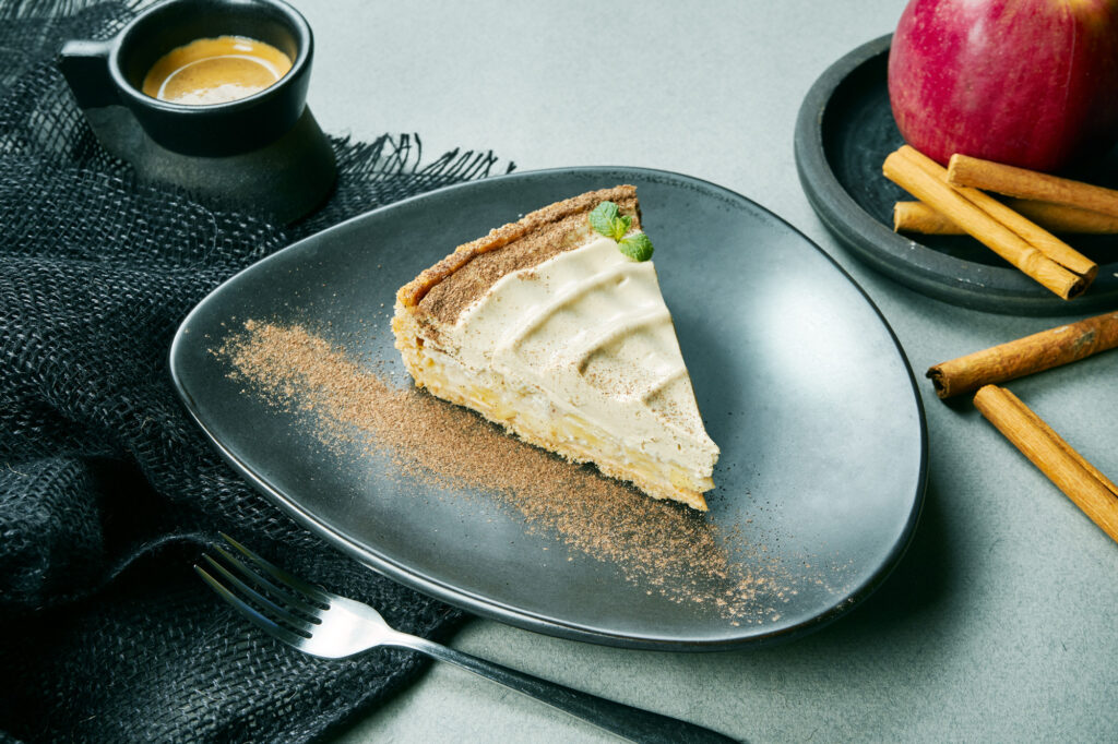 Churro cheesecake with cinnamon-sugar topping served on a white plate.