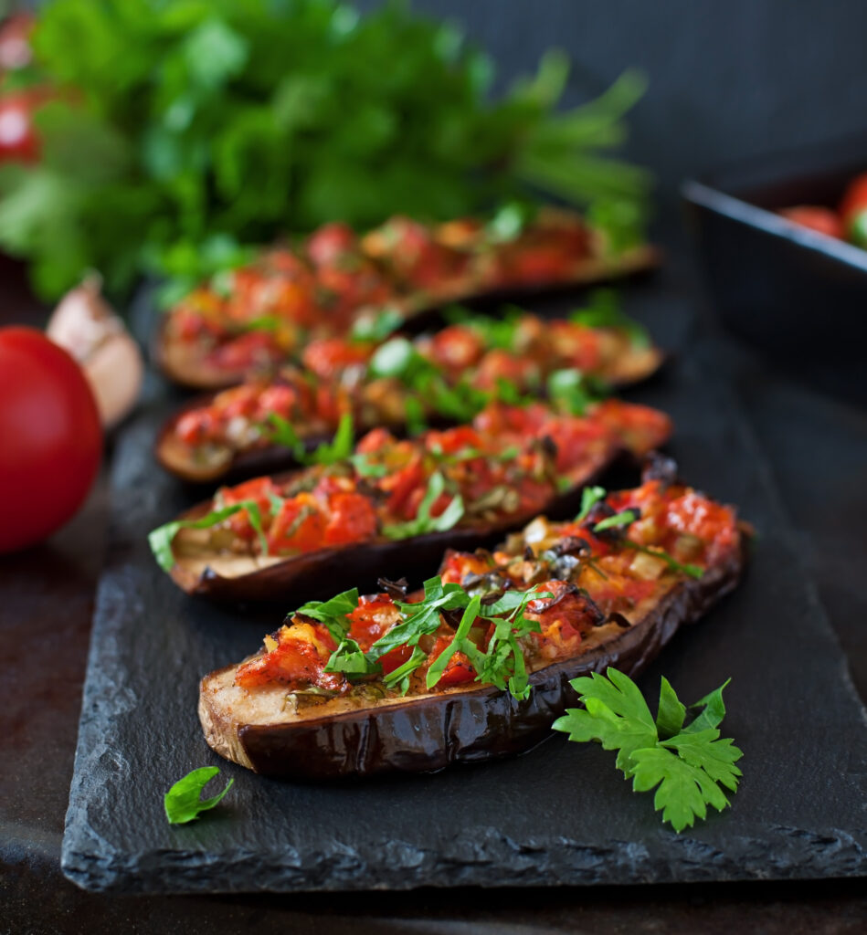 A beautifully plated vegan eggplant Parmesan with layers of crispy breaded eggplant, marinara sauce, and melted vegan cheese, garnished with fresh basil.