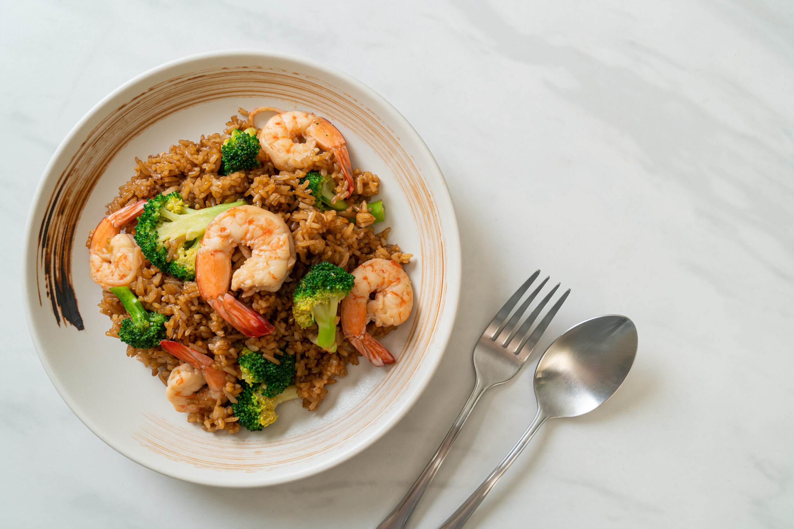 A vibrant bowl of healthy fried rice with brown rice, colorful vegetables, and green onions.