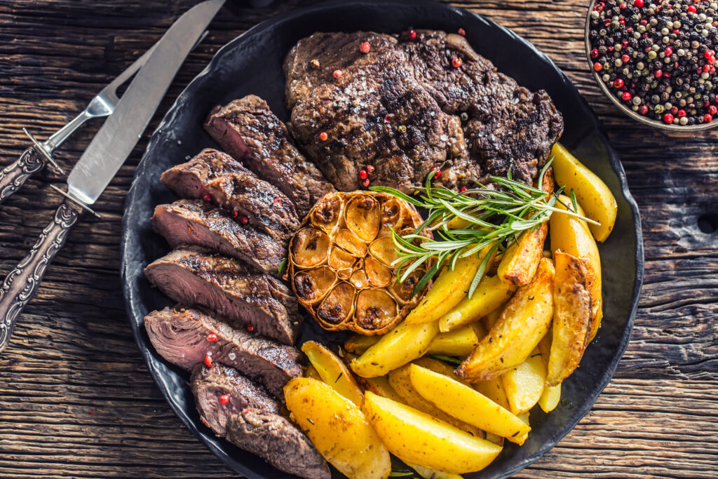 Perfectly cooked steak paired with roasted potatoes, garnished with herbs for a delicious, hearty meal.