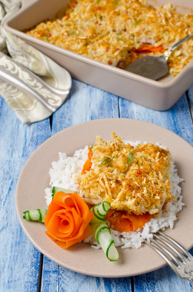 A baked tuna rice casserole topped with golden breadcrumbs and garnished with parsley in a casserole dish.