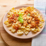 A steaming bowl of cheeseburger macaroni with creamy cheese sauce, ground beef, and pasta, topped with fresh parsley for a comforting and hearty meal.