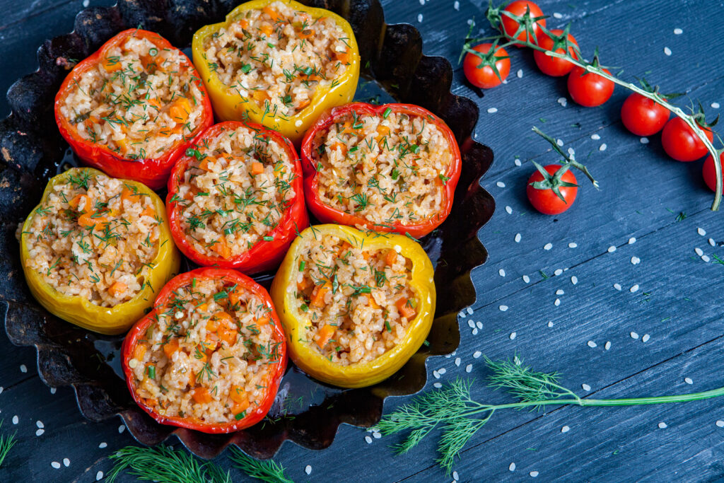 Colorful stuffed bell peppers filled with seasoned ground turkey, rice, and vegetables, topped with melted cheese and garnished with fresh parsley.